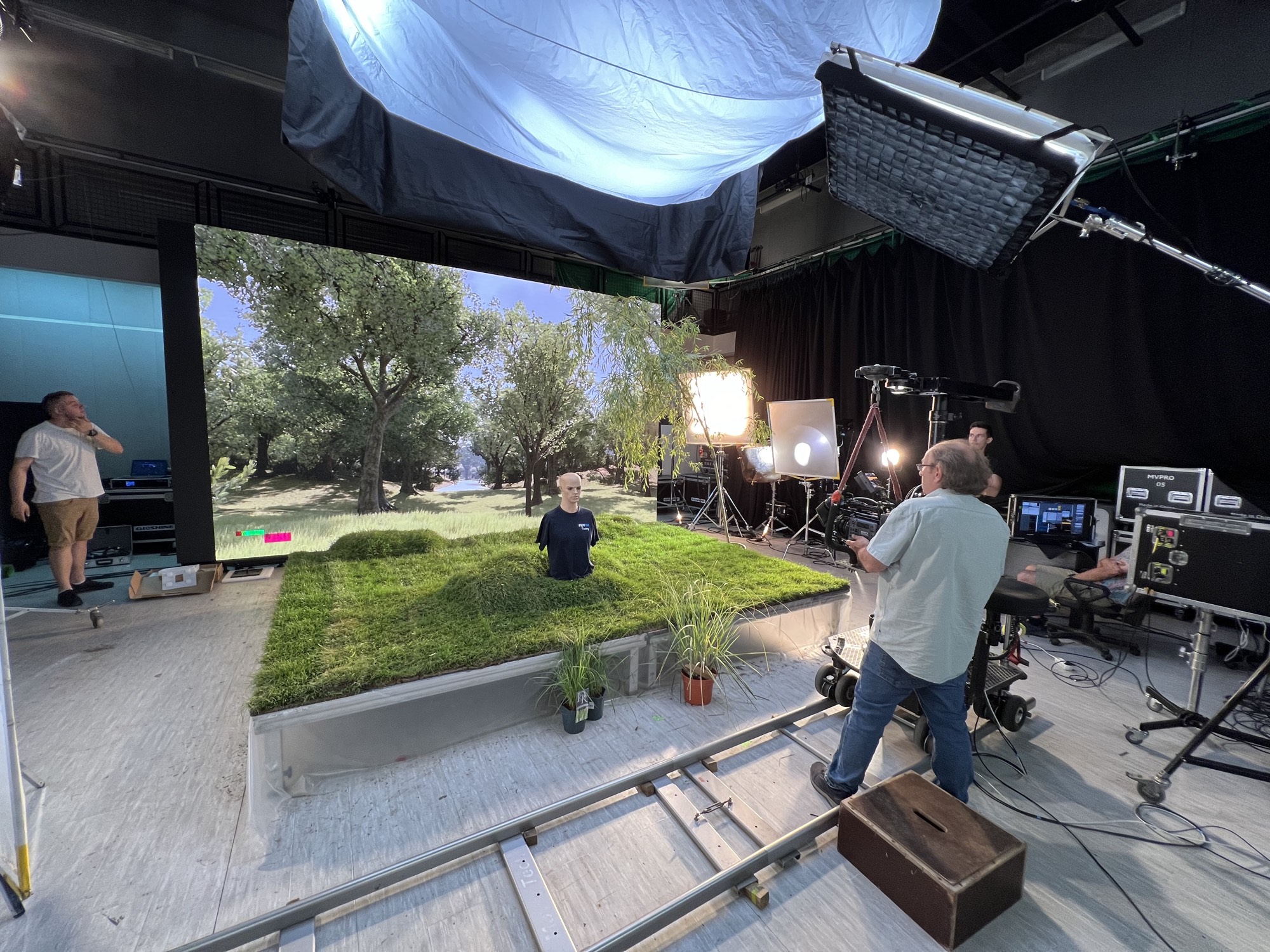 XR LED stage: an Unreal Engine orchard on the LED wall, real turf and plants built out onto the floor, camera on a dolly track