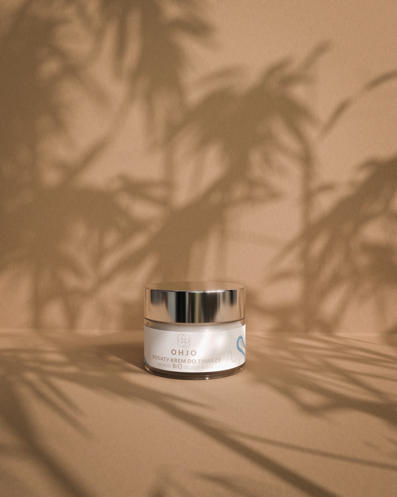 OHJO cream jar on a warm terracotta background with palm leaf shadows